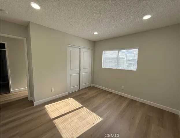 an empty room with wooden floor closet and windows