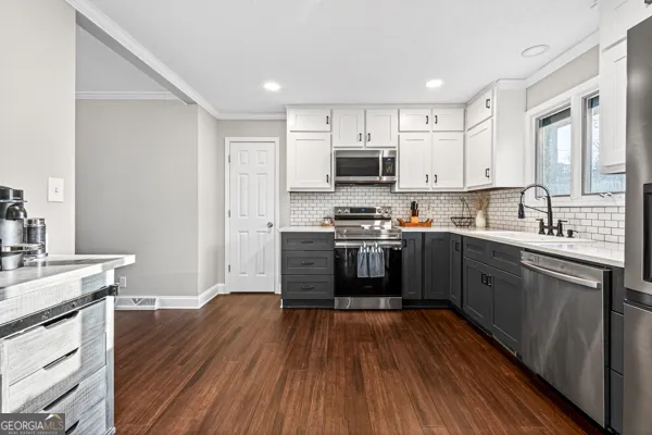 a kitchen with stainless steel appliances a sink dishwasher a refrigerator a stove top oven a wooden floor and cabinets