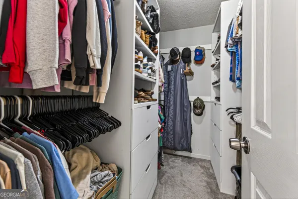 a view of walk in closet with clothes and shoes