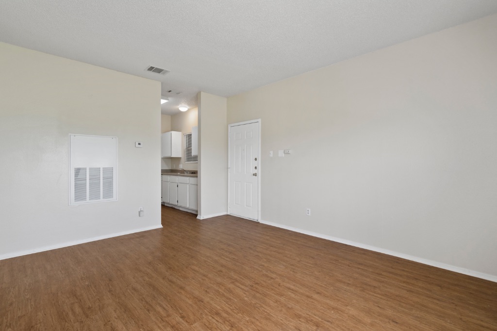 12166 Metric Boulevard, Unit 1013 Austin, TX 78758 - Photo 5 of 16 Unfurnished living room featuring dark wood finished floors and a textured ceiling