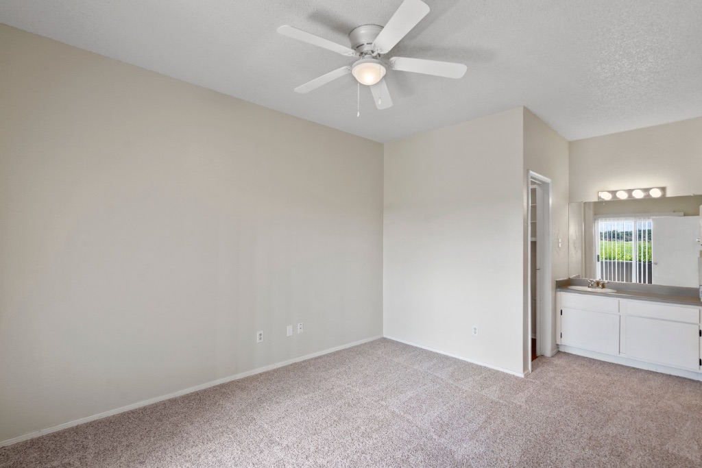 12166 Metric Boulevard, Unit 1013 Austin, TX 78758 - Photo 8 of 16 Unfurnished bedroom with light carpet, a ceiling fan, and a textured ceiling