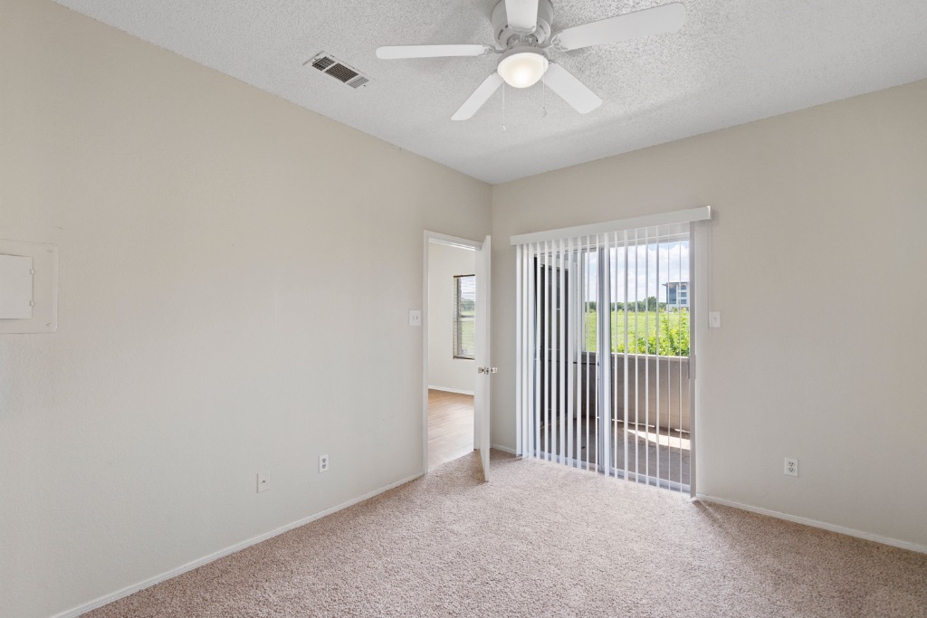12166 Metric Boulevard, Unit 1013 Austin, TX 78758 - Photo 9 of 16 Empty room featuring carpet floors, a textured ceiling, and ceiling fan