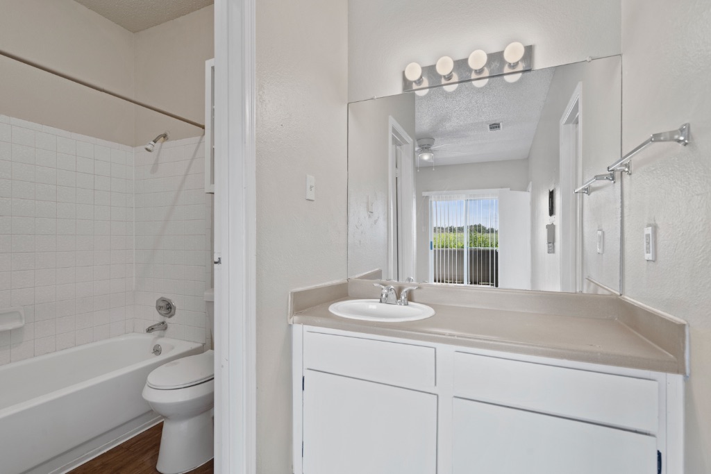 12166 Metric Boulevard, Unit 1013 Austin, TX 78758 - Photo 10 of 16 Bathroom with a textured ceiling, bathing tub / shower combination, vanity, a textured wall, and dark wood-style flooring