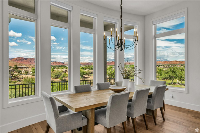 2608 Canyon Ridge Drive St. George, UT 84770 - Photo 18 of 86 Dining area featuring abundant natural light from multiple tall windows, a wrought iron chandelier, hardwood flooring, and distant mountain scenery