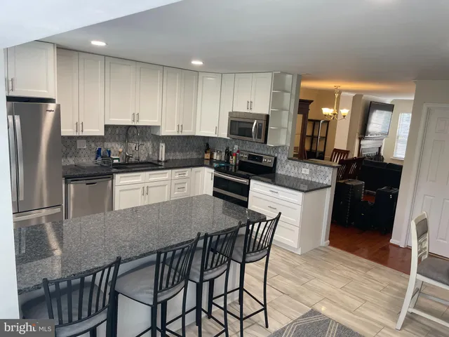 a kitchen with stainless steel appliances granite countertop a refrigerator a stove a sink a dining table and chairs