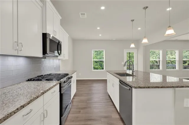 a kitchen with stainless steel appliances granite countertop a sink a stove and a wooden floors