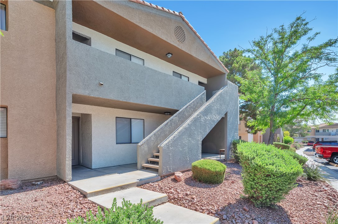 Rear view of property featuring stairs and stucco siding