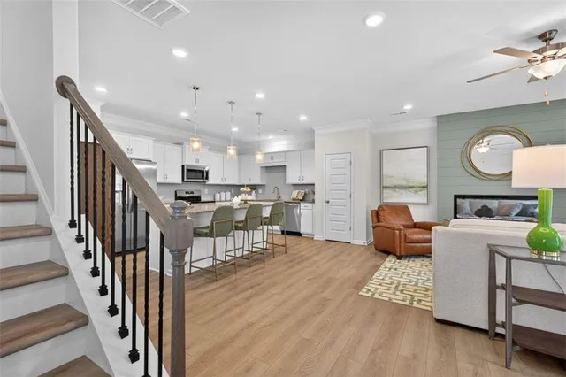 a living room with furniture kitchen view and a wooden floor