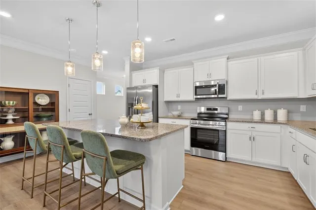 a kitchen with stainless steel appliances granite countertop a stove top oven a refrigerator a sink and a chairs