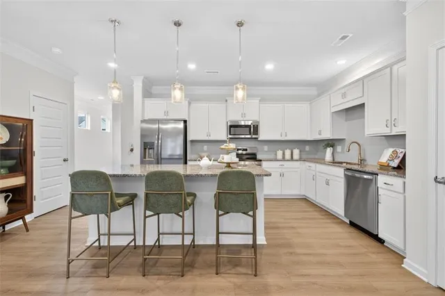 a kitchen with stainless steel appliances kitchen island granite countertop a dining table chairs and white cabinets