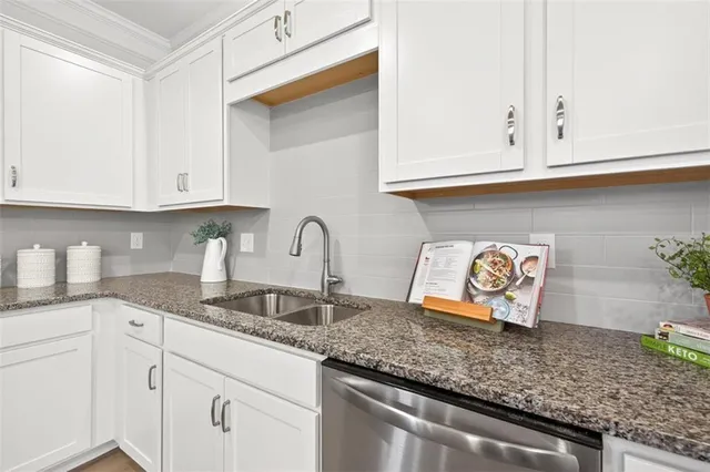 a kitchen with granite countertop white cabinets and sink