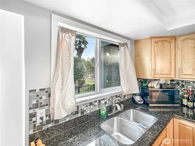 a kitchen with stainless steel appliances granite countertop a refrigerator a sink and white cabinets with wooden floor