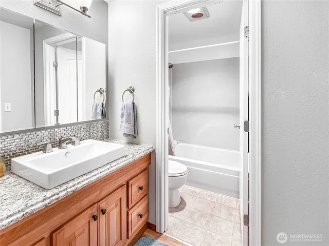 a bathroom with a granite countertop toilet a sink and a bathtub
