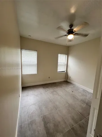 an empty room with a ceiling fan and window