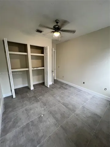 a view of an empty room with a cabinet and a ceiling fan