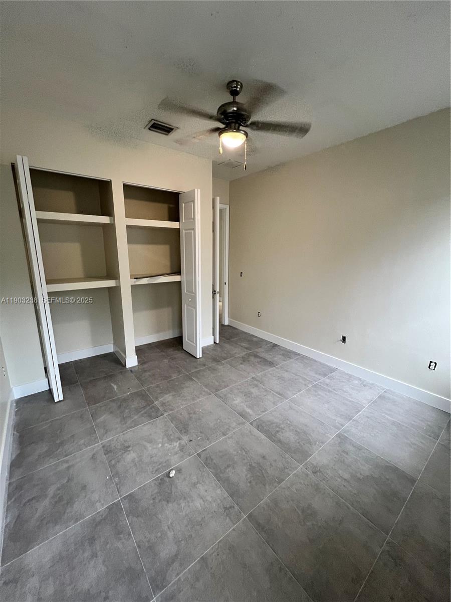 10274 Southwest 180th Street, Unit 1 Miami, FL 33157 - Photo 6 of 17 a view of an empty room with a cabinet and a ceiling fan