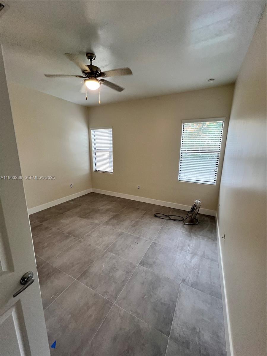 10274 Southwest 180th Street, Unit 1 Miami, FL 33157 - Photo 7 of 17 an empty room with windows and ceiling fan