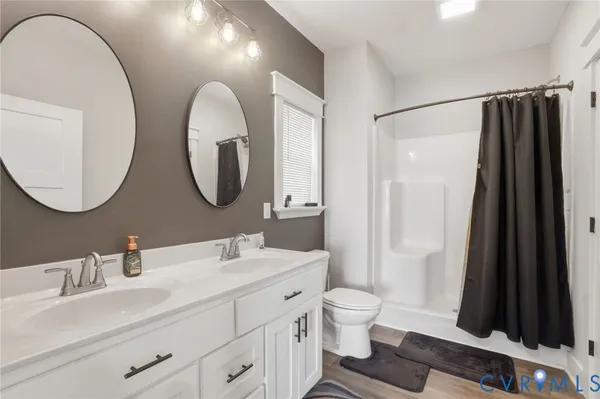 a bathroom with a double vanity sink toilet mirror and shower