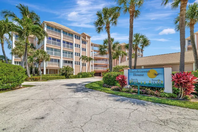 a front view of multi story residential apartment building with yard and sign board