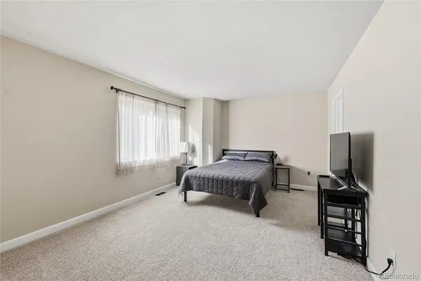 a spacious bedroom with a bed and a flat screen tv