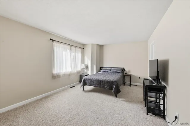 a spacious bedroom with a bed and a flat screen tv