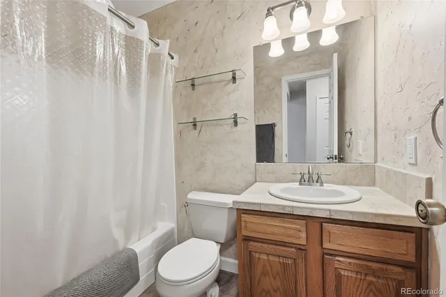 a bathroom with a granite countertop sink toilet a mirror and shower