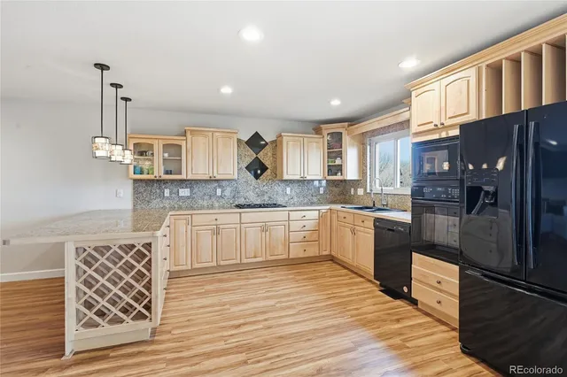 a large kitchen with stainless steel appliances kitchen island granite countertop a refrigerator a oven and a sink with wooden floor