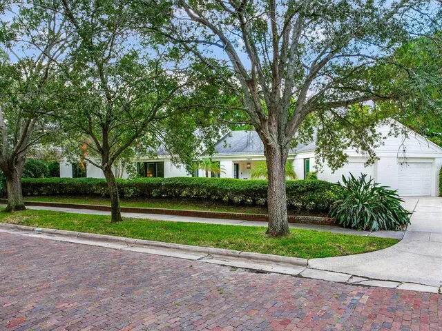 a view of a house with a yard and large trees