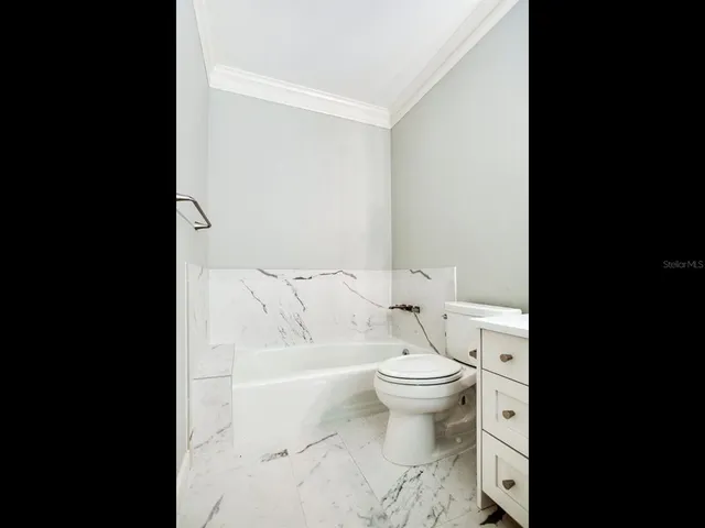 a bedroom with a bed a table and chair with wooden floor
