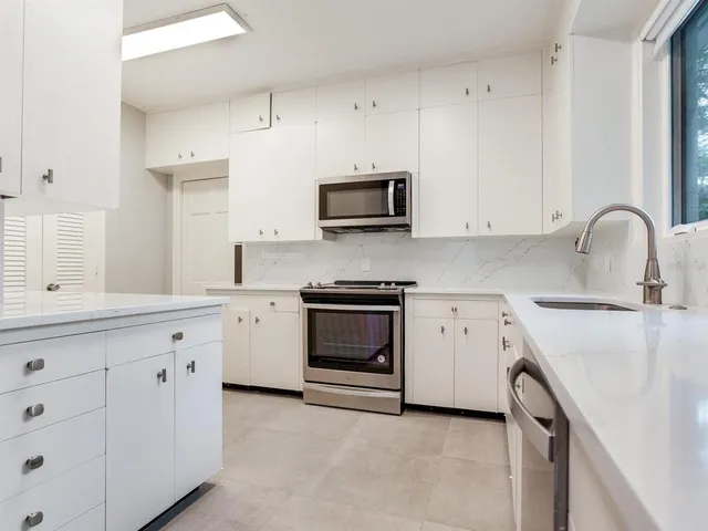 a kitchen with granite countertop white cabinets and stainless steel appliances
