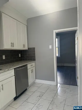 a kitchen with granite countertop white cabinets and stainless steel appliances
