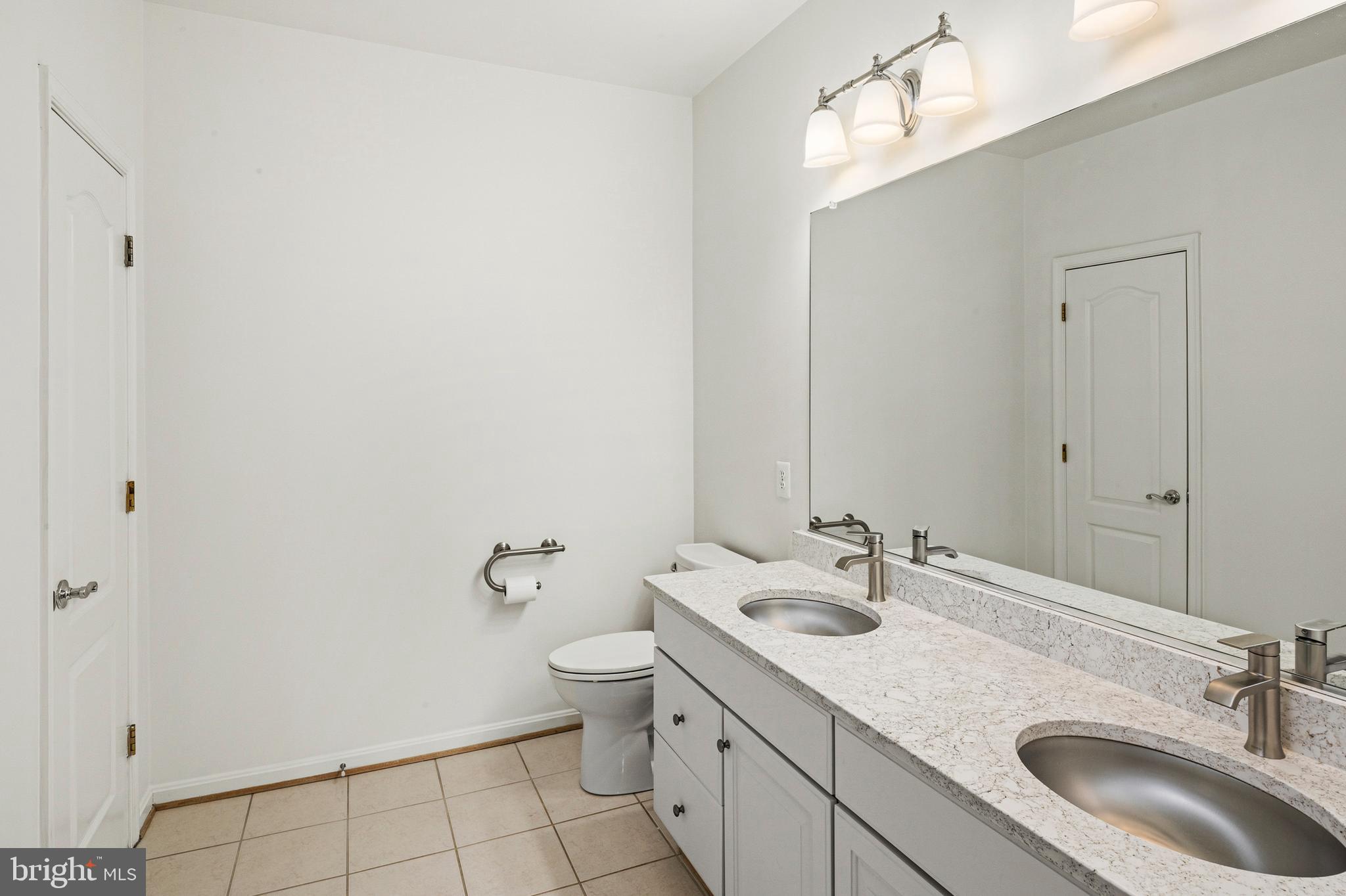 8601 Roaming Ridge Way, Unit 304 Odenton, MD 21113 - Photo 18 of 40 a bathroom with a granite countertop sink a toilet and a mirror