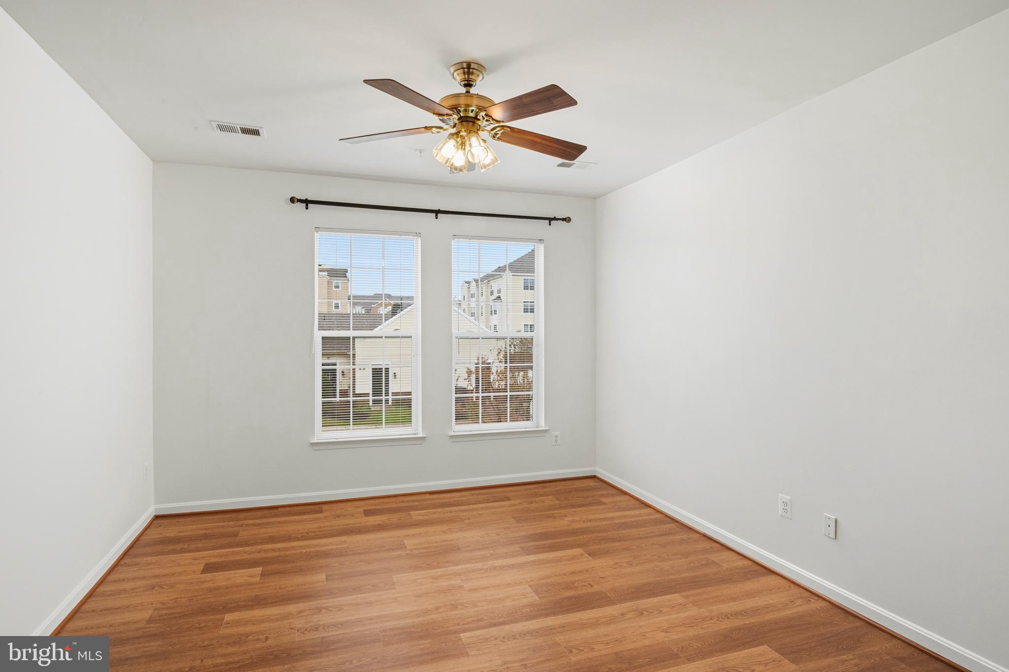 8601 Roaming Ridge Way, Unit 304 Odenton, MD 21113 - Photo 21 of 40 an empty room with wooden floor chandelier fan and windows