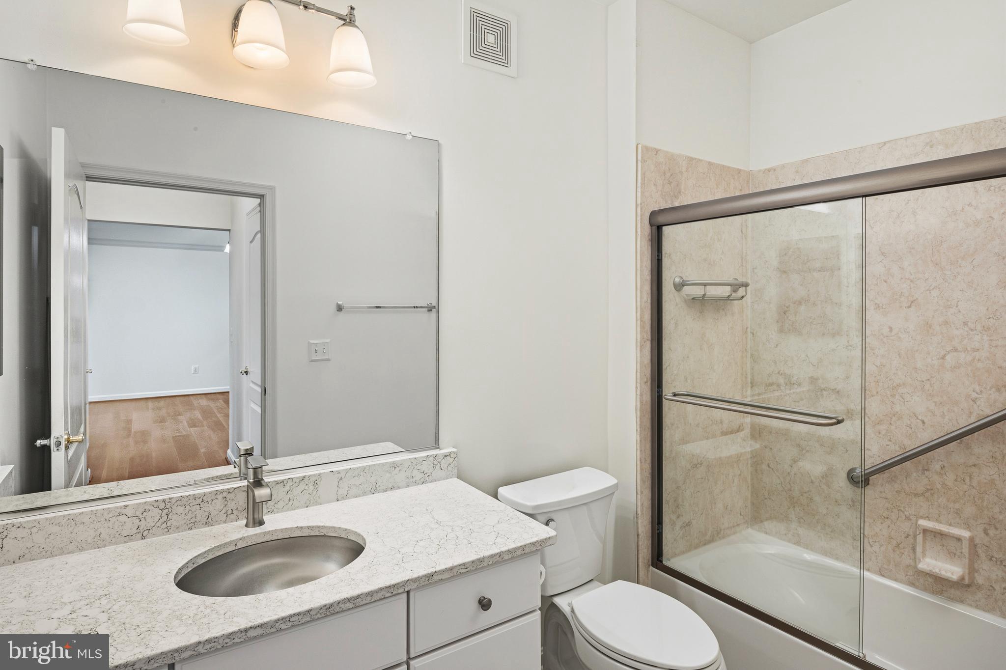 8601 Roaming Ridge Way, Unit 304 Odenton, MD 21113 - Photo 23 of 40 a bathroom with a sink toilet a mirror and shower