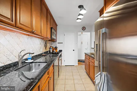 a kitchen with granite countertop a sink a stove and refrigerator