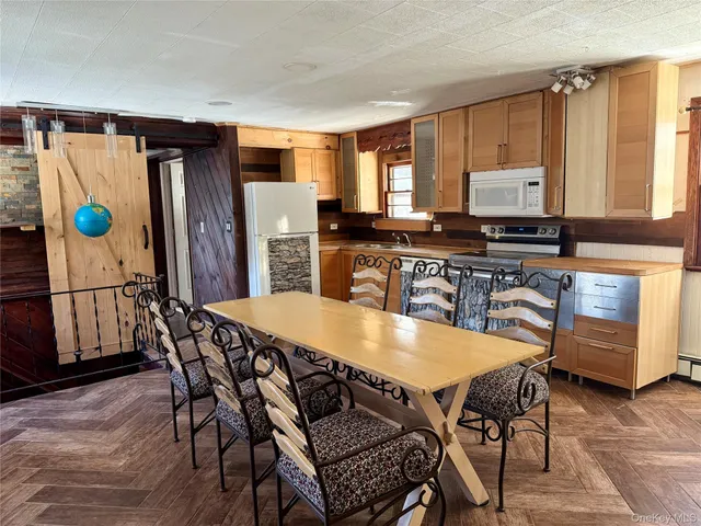 a dining hall with stainless steel appliances granite countertop a table chairs and a refrigerator