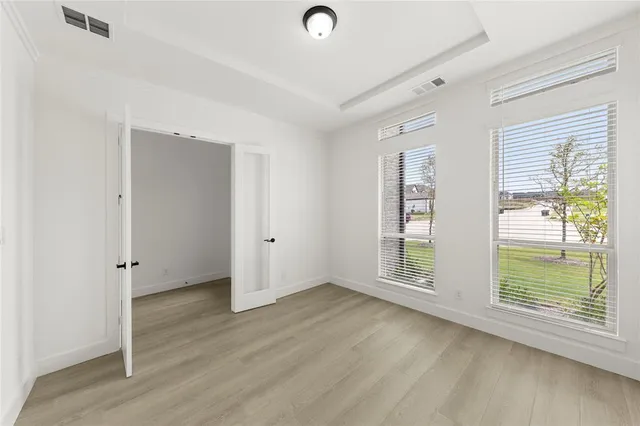 an empty room with wooden floor and windows