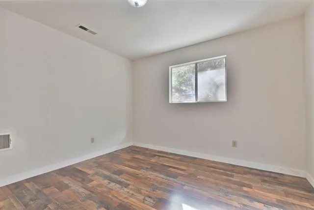 a view of empty room with wooden floor