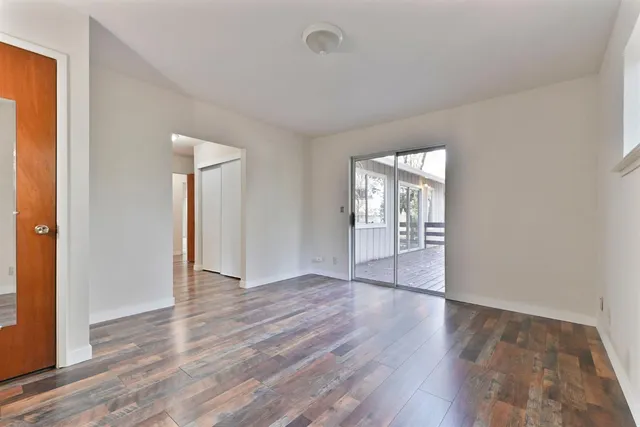 a view of an empty room with window and wooden floor