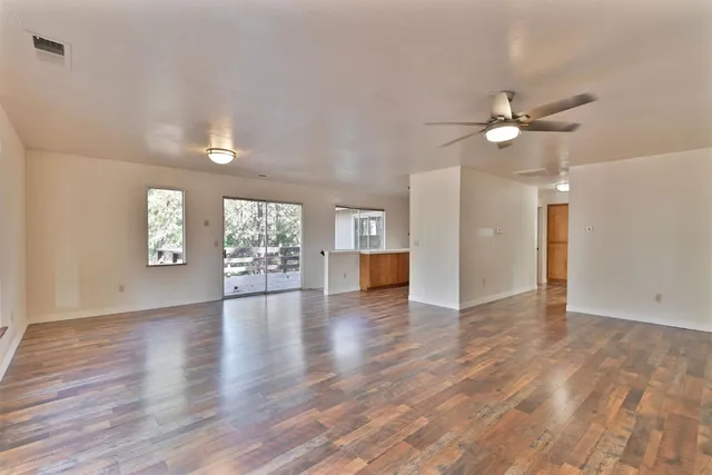 a view of an empty room with window and wooden floor