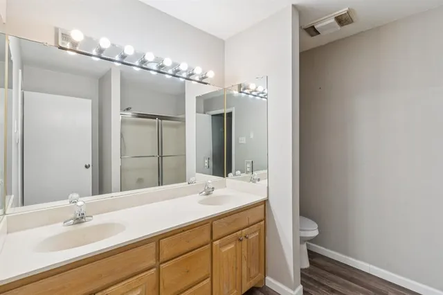 a bathroom with a double vanity sink mirror and toilet