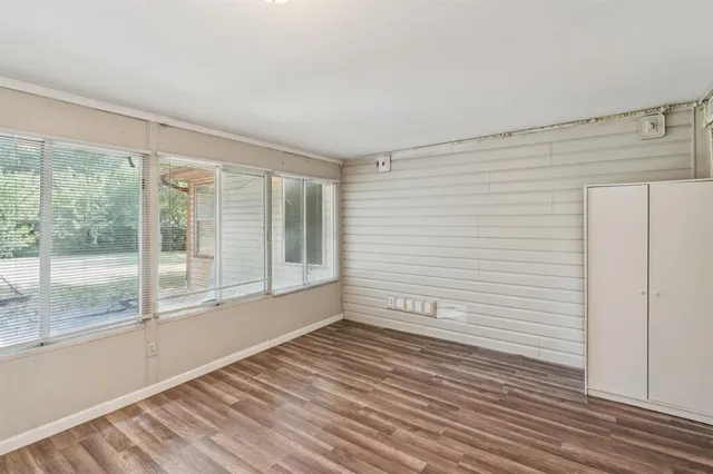 a view of empty room with wooden floor and fan