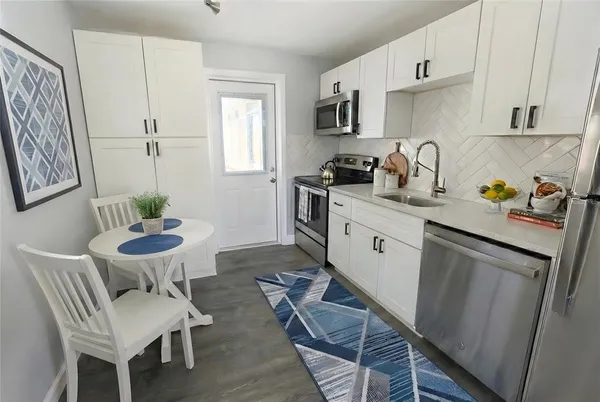 a kitchen with stainless steel appliances a white table chairs and a refrigerator