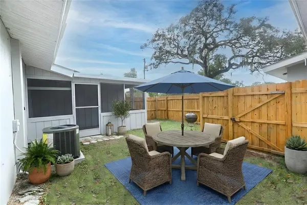 a view of a patio with couches table and chairs under an umbrella