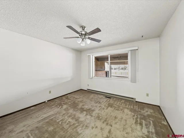 an empty room with a ceiling fan and window