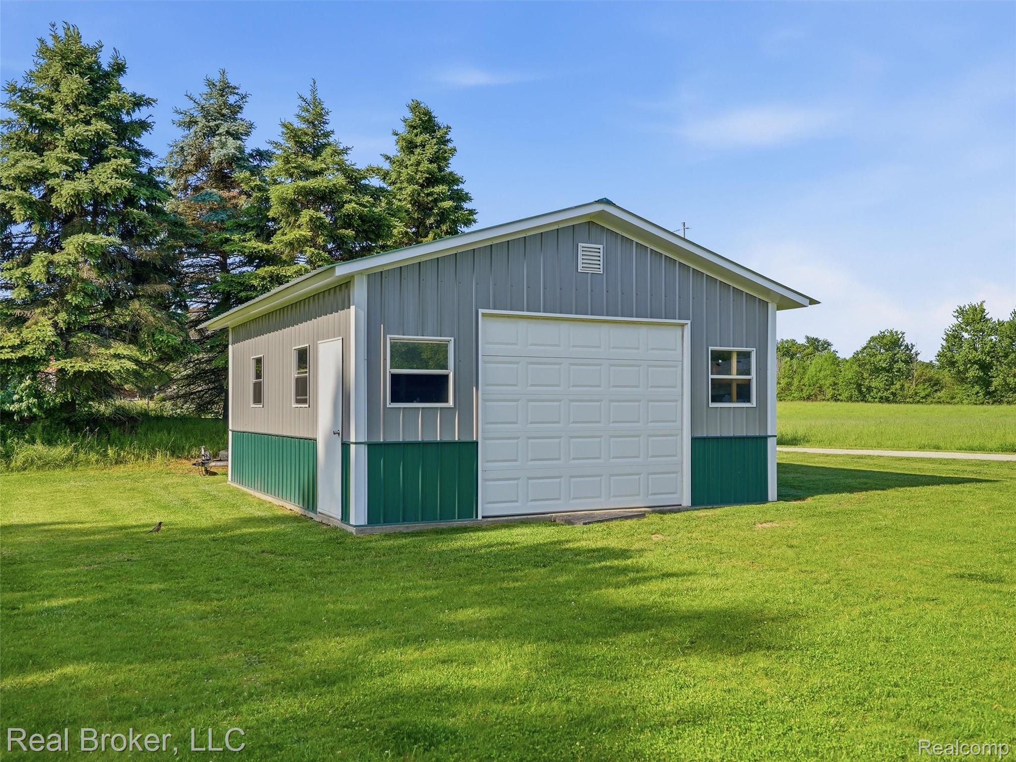 7271 West Ray Road Gaines, MI 48436 - Photo 11 of 48 Metal-sided auxiliary building featuring a prominent white overhead door and a pedestrian entry door
