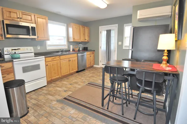 a kitchen with stainless steel appliances granite countertop a stove a sink dishwasher a dining table and chairs with wooden floor