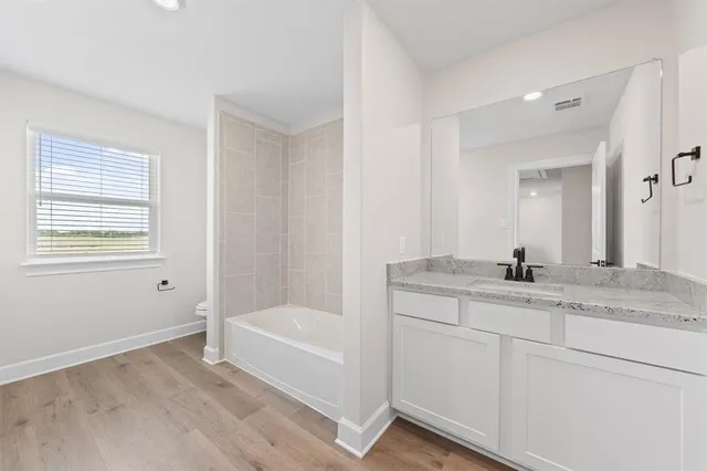 a bathroom with a granite countertop sink a mirror and a bathtub