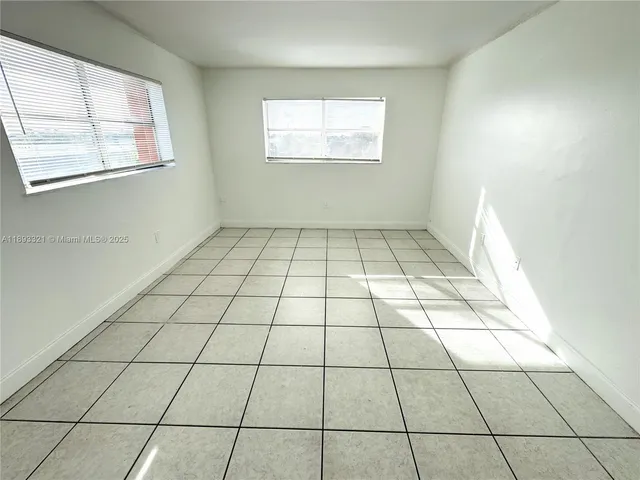 a view of an empty room with window and a bathroom