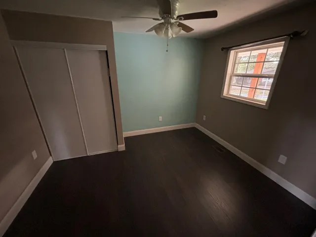 an empty room with wooden floor cabinet and windows